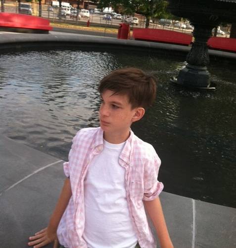 Boy sitting on edge of fountain