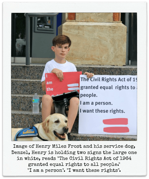 Image of Henry Miles Frost and his service dog, Denzel, Henry is holding two signs the large one in white, reads "The Civil Rights Act of 1964 granted equal rights to all people." "I am a person". "I want these rights".