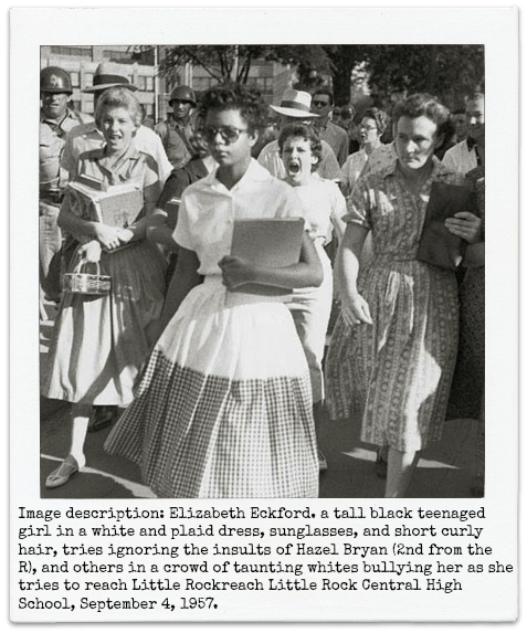 Image description: Elizabeth Eckford. a tall black teenaged girl in a white and plaid dress, sunglasses, and short curly hair, tries ignoring the insults of Hazel Bryan (2nd from the R), and others in a crowd of taunting whites bullying her as she tries to reach Little Rockreach Little Rock Central High School, September 4, 1957