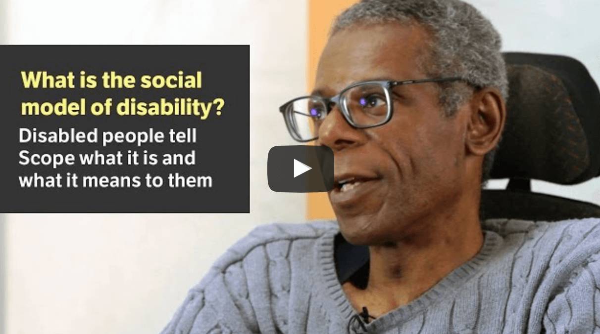 A man with brown skin and gray hair wearing glasses and sitting in a wheelchair talking. Text reads 
