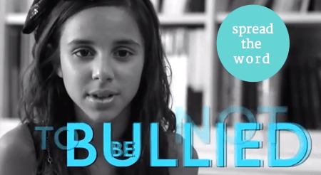 Image description black and white photo of girl with long brown hair looking at the camera . blue text reads"BULLIED" and NOT in background. Upper right hand corner of image has green circle with with white text that reads "spread the word"